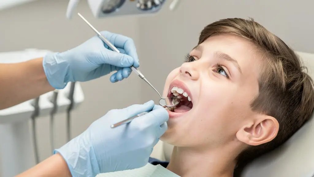 Gros plan sur l'examen dentaire d'un enfant par un orthodontiste utilisant des instruments professionnels