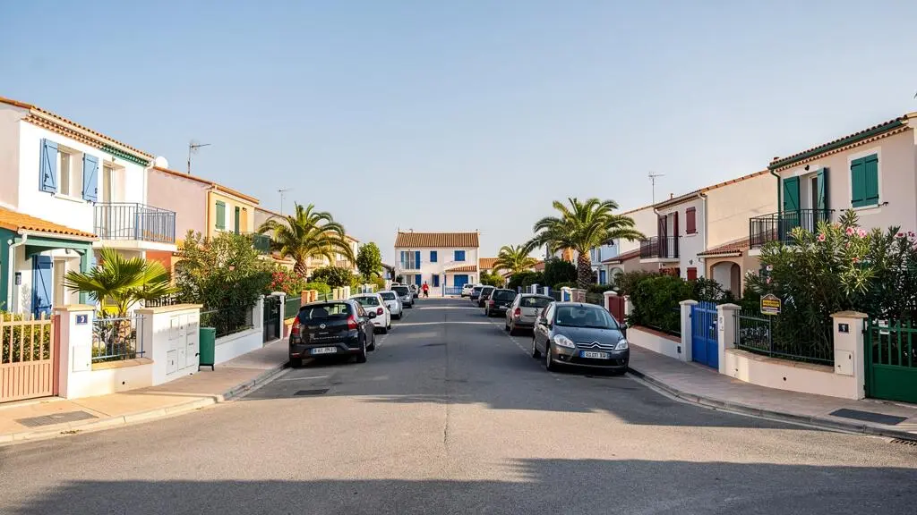 Rue résidentielle calme du Grau-du-Roi bordée de maisons de vacances typiques et de végétation méditerranéenne